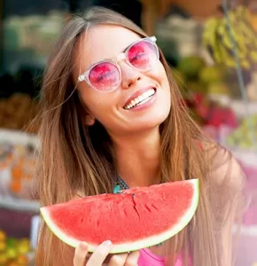young lady smiling while holding watermelon