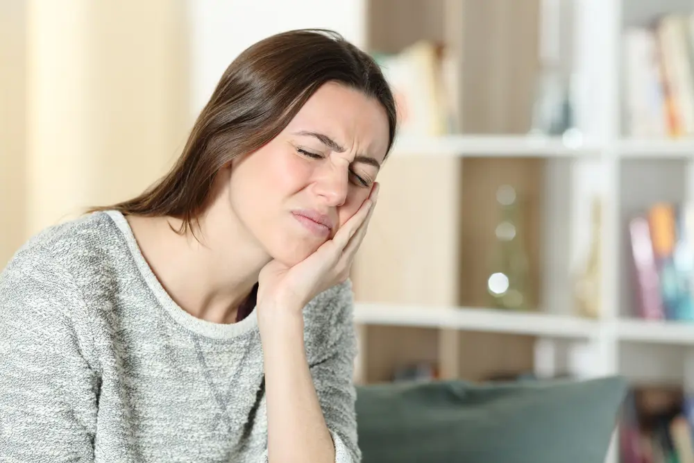 Woman wincing and holding her lower jaw looking for a TMJ specialist near Los Angeles